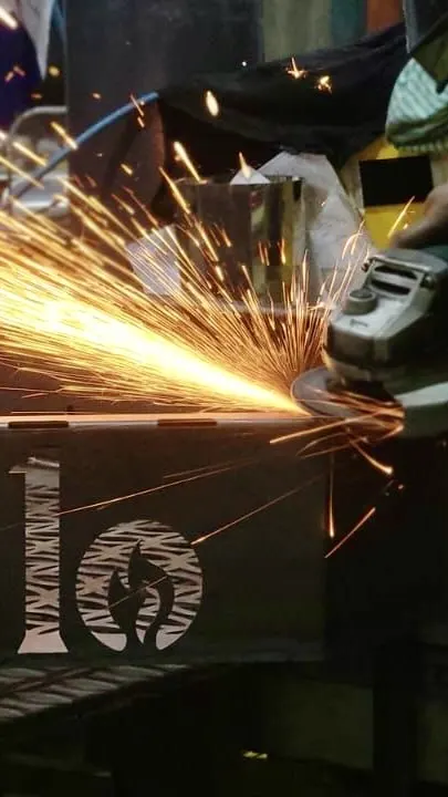 Grinding steel on an Exit 10 smoker in the UAE workshop, the Exit 10 logo cut into the steel